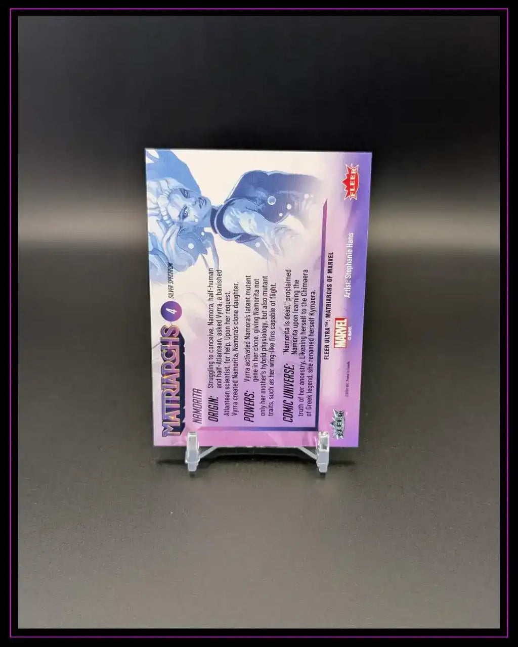 Rückseite einer Marvel Trading Card mit lila Design, Text und Comic-Figuren, auf Ständer